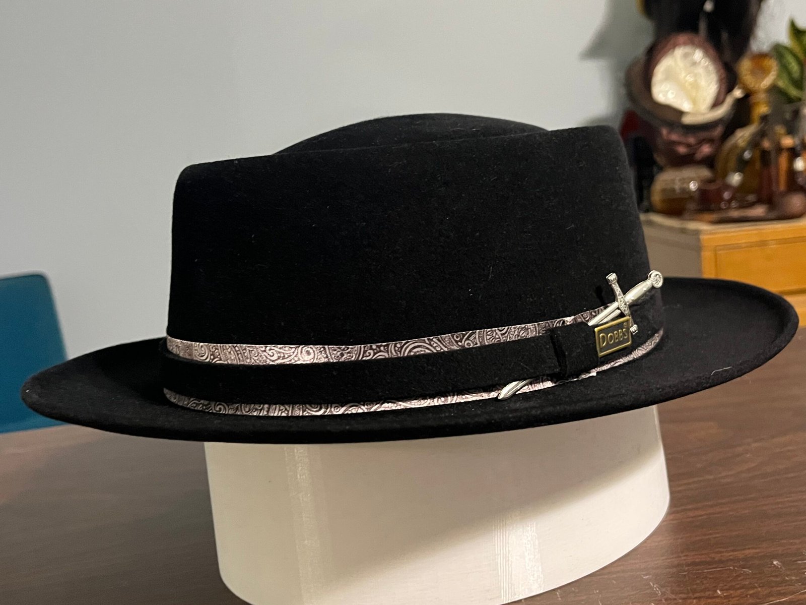 Finished black Dobbs fur felt pork pie from project PM-26-005, showing the paisley accent band and Maker’s Sword ornament.