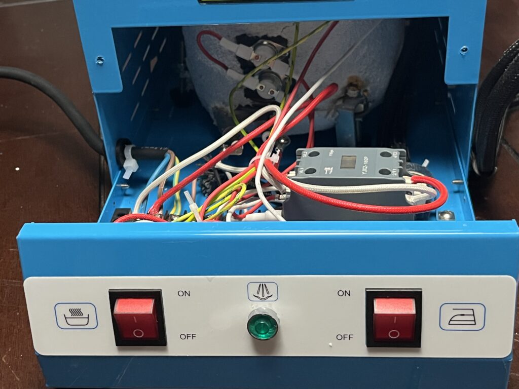 Interior view of the ST-750 showing multiple red, white, black, blue, brown, and green-yellow electrical conductors routed around the boiler, contactor, terminal strip, and controls