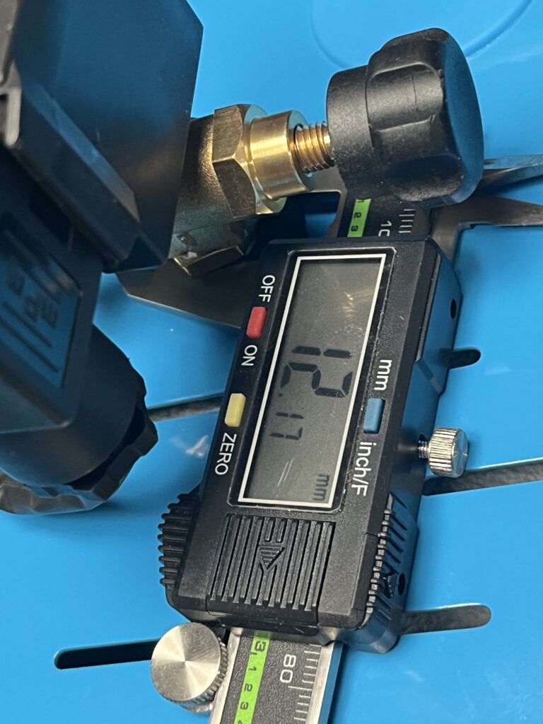 Digital caliper measuring the exposed threaded stem of the ST-750 steam-adjustment valve at 12.17 mm.