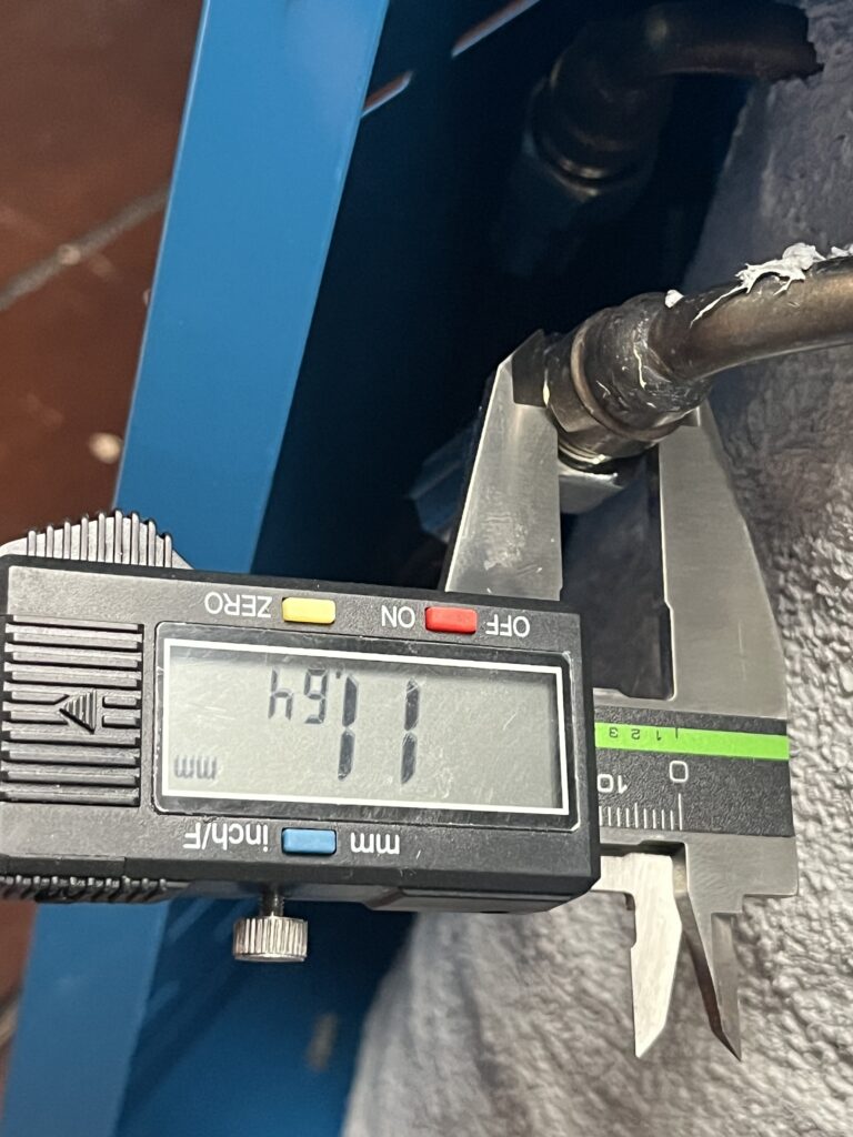 Digital caliper measuring a boiler-mounted ST-750 steam-system connection at 11.64 mm.
