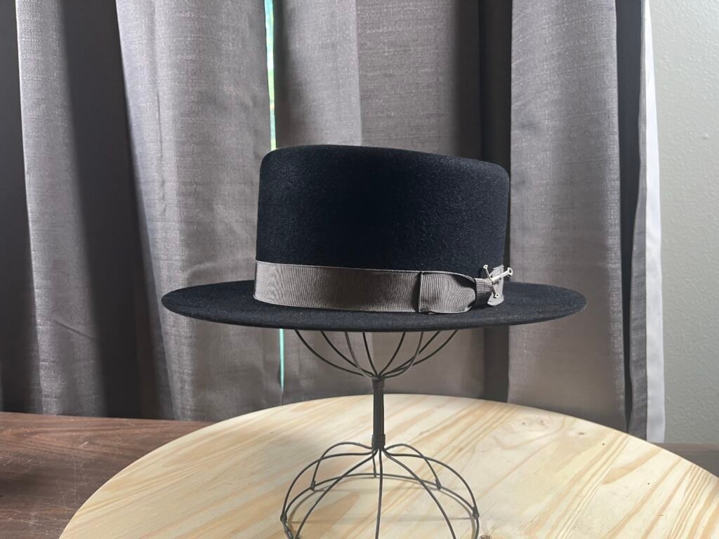 Finished black 100% rabbit pork pie with gray grosgrain ribbon, bow, and Maker’s Sword, Project PM-26-010.