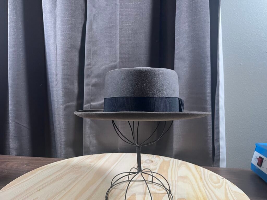 Front view of the finished gray 100% beaver pork pie showing the crown profile, brim, and black grosgrain hatband.