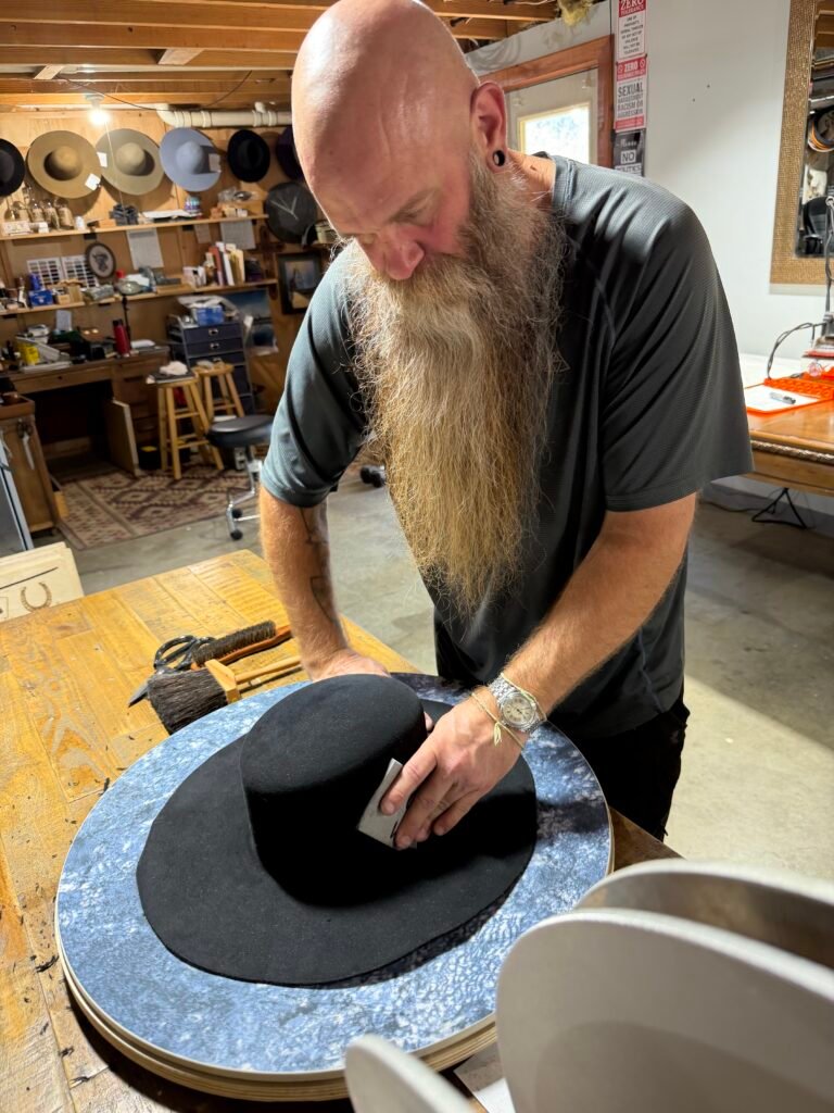Pouncing the black 100% rabbit felt body during construction of Project PM-26-010.