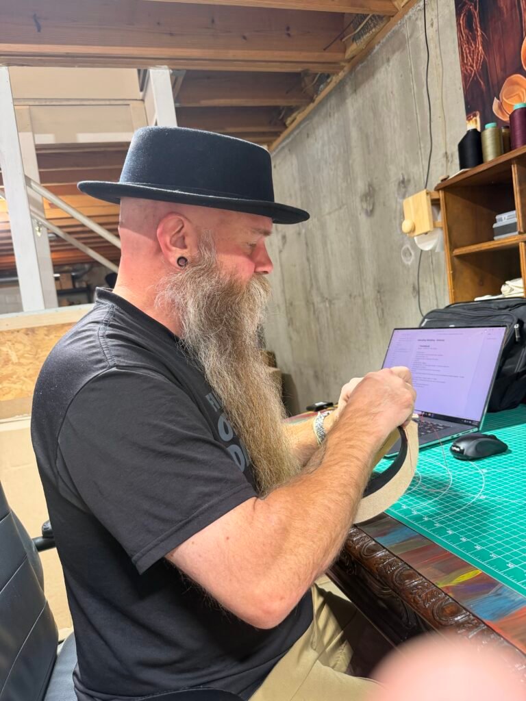Hand sewing the prepared leather sweatband during construction of Project PM-26-010.