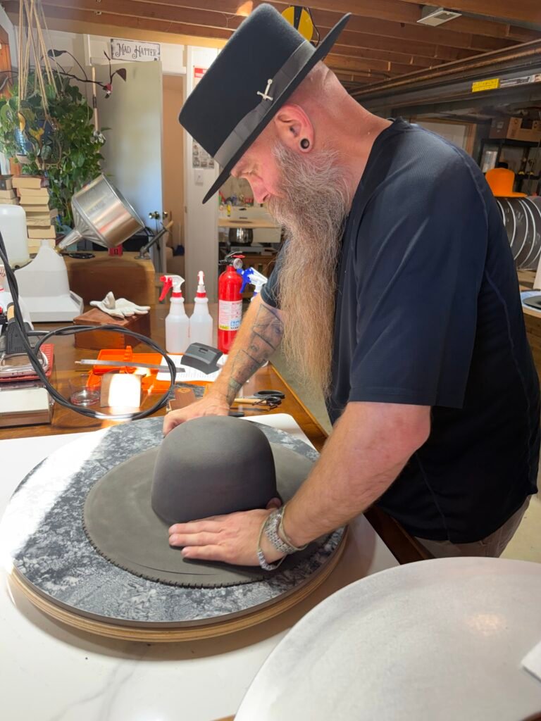 Cutting the brim of the 100% beaver felt hat to its final width during construction of Project PM-26-011.