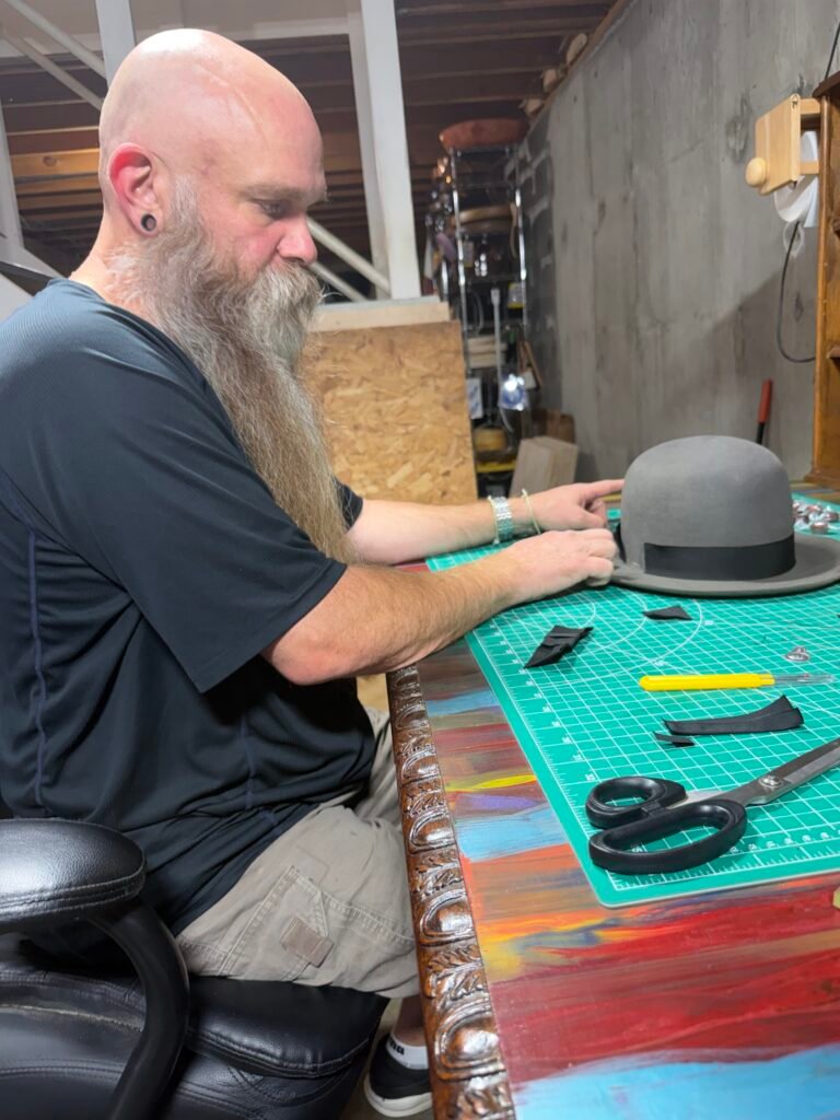 Installing the ribbon and trim on the 100% beaver pork pie during construction of Project PM-26-011.